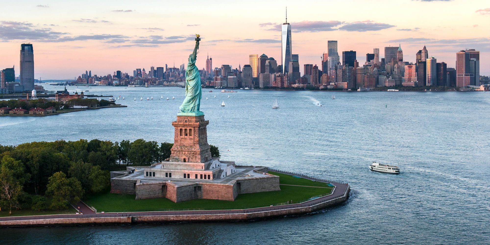 Vrijheidsbeeld op Liberty Island in New York City, met op de achtergrond de skyline van Manhattan inclusief het One World Trade Center.