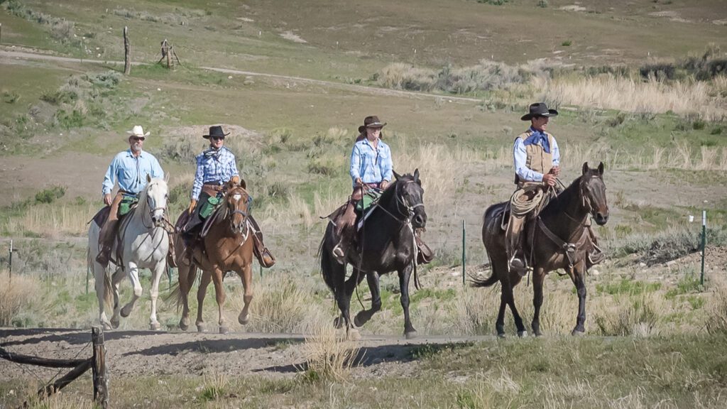 4 ruiters met cowboyhoed rijden achter elkaar