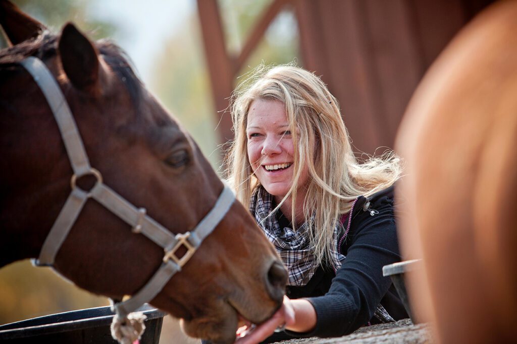 een vrouw die een paard aait